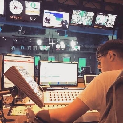 Alex Healey working at a studio desk surrounded by monitors